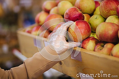 Close-up of females hand in protective gloves hold beautiful fresh apple in hand. Shopping during quarantine Stock Photo