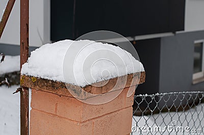 A fence post with snow at a metal fence Stock Photo