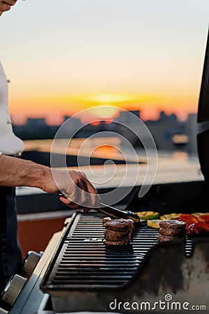 Close-up of filet mignon vegetables and meat on a bbq grill on a skyscraper rooftop at sunset. Fire in the barbecue Stock Photo