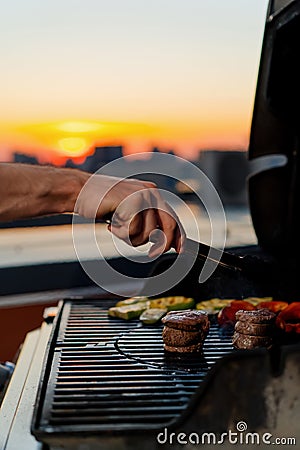 Close-up of filet mignon vegetables and meat on a bbq grill on a skyscraper rooftop at sunset. Fire in the barbecue Stock Photo