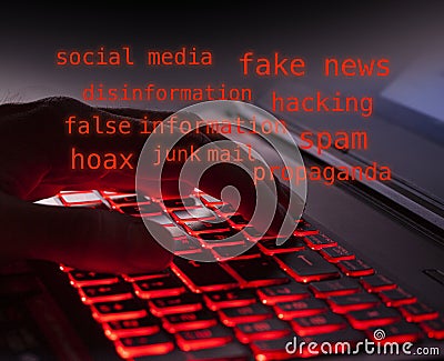 Close up of fingers typing on glowing red backlight keys on a computer keyboard in the dark. Glowing red text about computer hacke Stock Photo