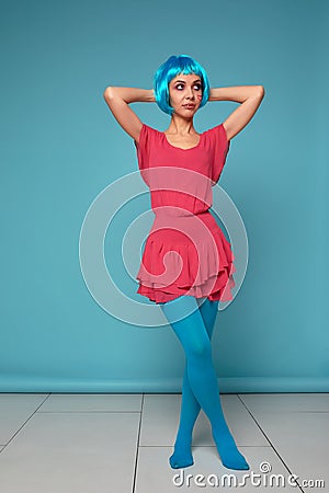 Close up of a flirtatious female model on blue background wearing a blue wig. Pretty glamorous woman pink hair charm Stock Photo