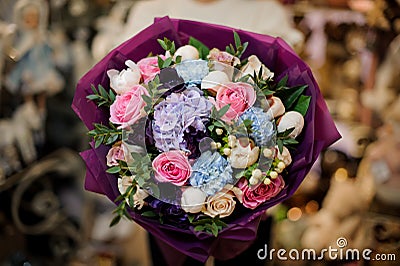 Close-up on flowers of gorgeous bouquet wrapped in purple paper Stock Photo