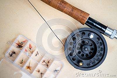 Close up of fly fishing rod with reel next to box with tied flies. Fly fishing equipment still life. Nobody Stock Photo