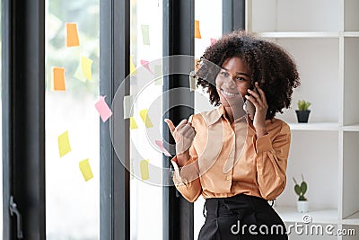 African American female employee write down on colorful sticky notes manage list, concentrated biracial woman work on Stock Photo