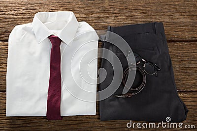Folded school uniform, belt and spectacle on wooden plank Stock Photo
