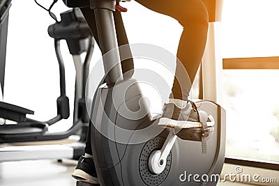 Close up foot biking in gym, exercising legs doing cardio workout cycling bikes Stock Photo