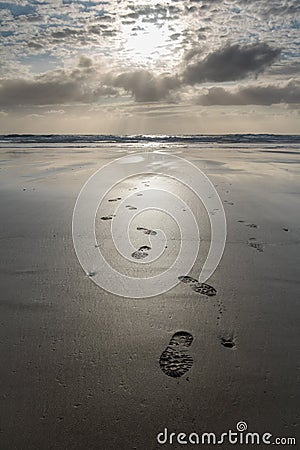 Close up on footsteps on sandy ground in beautiful golden sunset on biscarrosse beach, france Stock Photo