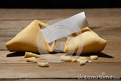 Close up of fortune cookie with blank paper inside and cookie crumbles on a bamboo board Stock Photo