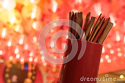 Close up of fortune sticks or Chi-Chi sticks, shake for future fore with red Chinese paper lamp in the background. Stock Photo