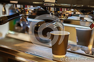 Close-up fresh espresso pours in paper cup, Italian espresso machine. Coffee culture and professional coffee making Stock Photo
