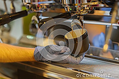 Close-up fresh espresso pours into porcelain cup in the hand of professional barista. Coffee culture and professional Stock Photo