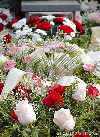 Close up of fresh floral wreaths made of pink and red roses on the grave after a funeral Stock Photo