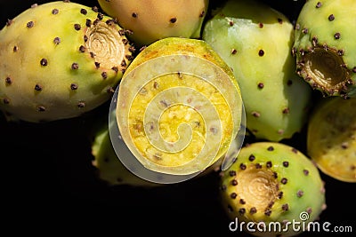Close-up of fresh prickly pears lying against dark background. The fruits fall sideways into the picture from above Stock Photo