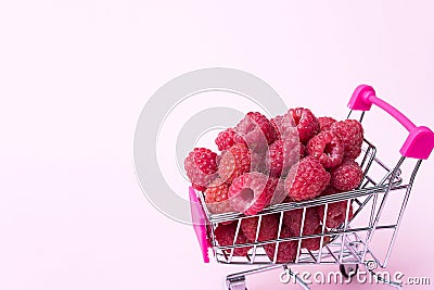 Close up fresh ripe raspberries in supermarket trolley, healthy eating concept, food background with summer berries Stock Photo