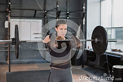 Close up front portriat of a woman is lifting weight while working out with barbell in gym. Stock Photo