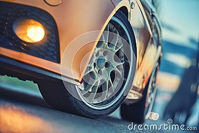 Close-up of front sports car wheel on the asphalt road at dusk cold light Stock Photo