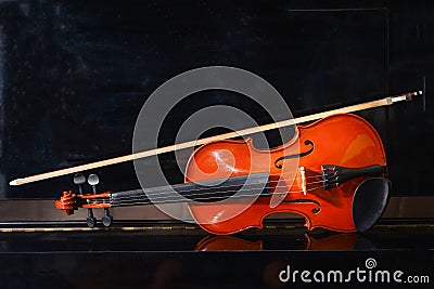 Close up front view violin on piano with black background. Stock Photo