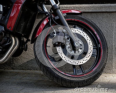 Close-up front wheel and fork of a modern beautiful motorcycle parked in the city street Editorial Stock Photo
