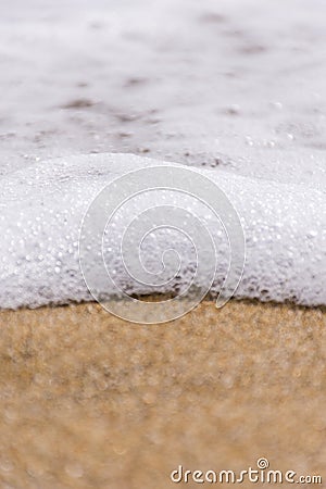 A close up of frothy waves on a stormy day against the golden sandy beach. Copy Paste Stock Photo