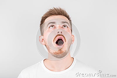 Close up of funny handsome young man with in stylish white t-shirt looking in camera with raised eyebrows and surprised face Stock Photo
