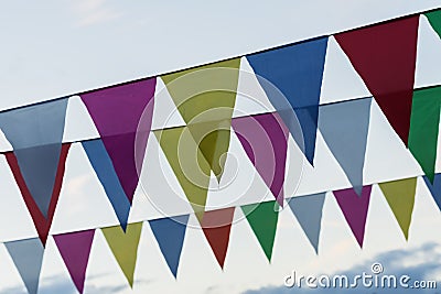 Close-up garland of colorful flags of triangular shape, pennants against blue sky. City street holiday. Modern Stock Photo