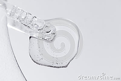 Close up of gel or serum glass pipette with transparent drops on white background Stock Photo