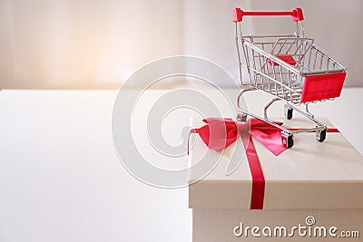 Close-up of gift boxes and shopping cart on white desk. Stock Photo