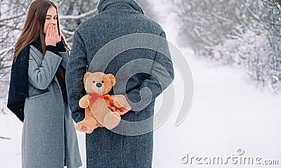 Close-up of gift, teddy bear with red ribbon. Young caucasian man holding behind his back to surprise his girlfriend Stock Photo