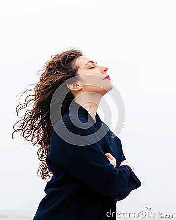 Girl rain sea wind winter portrait woman smile spring coat long hair curly mood shore snow beach Stock Photo