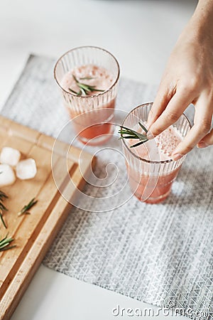 Close up of girl`s hands decorating grapefruit detox healthy smoothie with rosemary. Stock Photo