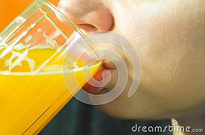 Close up of girls face and lips drinking orange juice from the glass as refreshment, real people, selective focus Stock Photo