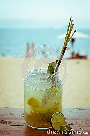 Close up of glass with refreshing lemongrass coctail with mint, lime on sea beach background Stock Photo