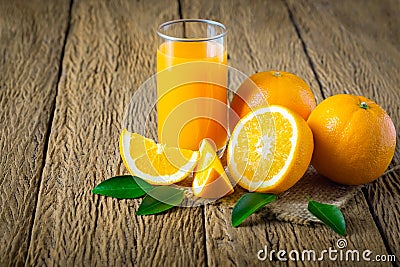 Close-up of Glass squeezed orange juice and fresh fruits ripe cut half, slice with green leaves on old wood vintage table. Stock Photo