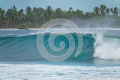 CLOSE UP: Glassy water droplets fly around a wave rolling towards exotic island Stock Photo