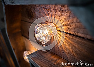 Close up of glowing illuminated electric bulb on rustic tall wooden wedding love letters casting lines of shadow outwards Stock Photo