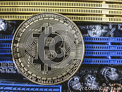 Close-up of gold bit coin, computer circuit board with bitcoin processor and microchips. Electronic currency, internet finance. Stock Photo