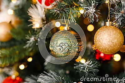 A close-up of gold and green glittering ornaments on a branch of a Christmas tree Stock Photo