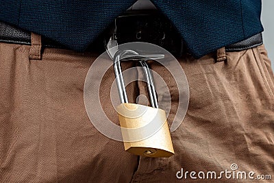 Close-up of a gold padlock hanging from a man`s belt. The concept of marital fidelity, celibacy, treason, chastity belt Stock Photo