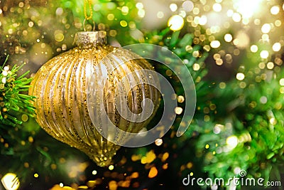 Close up of golden ball ornament hanging on decorated Christmas tree. Sparkling garland bokeh lights glitter. Magic cozy holiday Stock Photo
