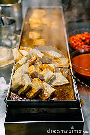 Close-up golden Fermented Tofu or Stinky Tofu on a hot plate with chili pepper spicy sauce, famous Taiwanese signature street food Stock Photo