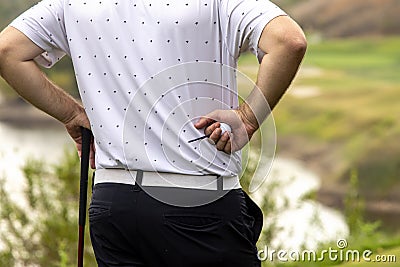 Close up of golfer holding golf ball and golf tee with golf course out of focus Editorial Stock Photo