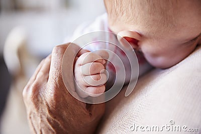 Close up of grandfather holding the hand of his baby grandson as he holds him, detail, elevated view Stock Photo