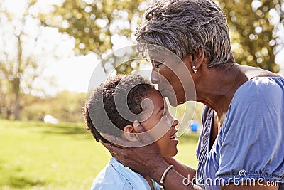 Close Up Of Grandmother Kissing Grandson In Park Stock Photo