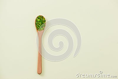 Close up of green softgel capsules with wooden spoon on isolated Stock Photo