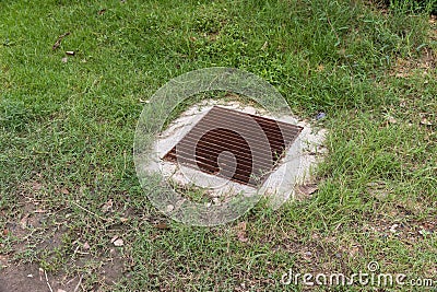 Close up Grille drain of sewer around the Grass field . Water recirculation system. Wastewater treatment. Stock Photo