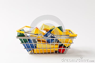 Close up of grocery basket for shopping in supermarket with yellow handles filled with multi-colored geometric shapes Stock Photo