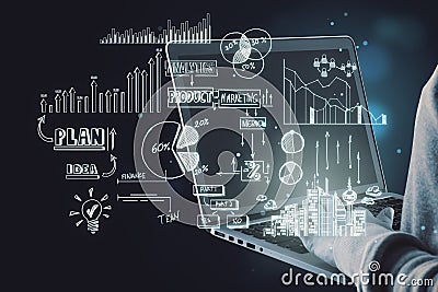 Close up of hacker hands holding and using laptop computer with creative toned business sketch on dark background. Business Stock Photo