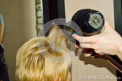 hairdresser dries hair with a hairdryer and styles Stock Photo