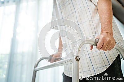 Close up hand of Asian Senior elderly disabled man patient walk slowly with walker at nursing home. Older handicapped male have Stock Photo